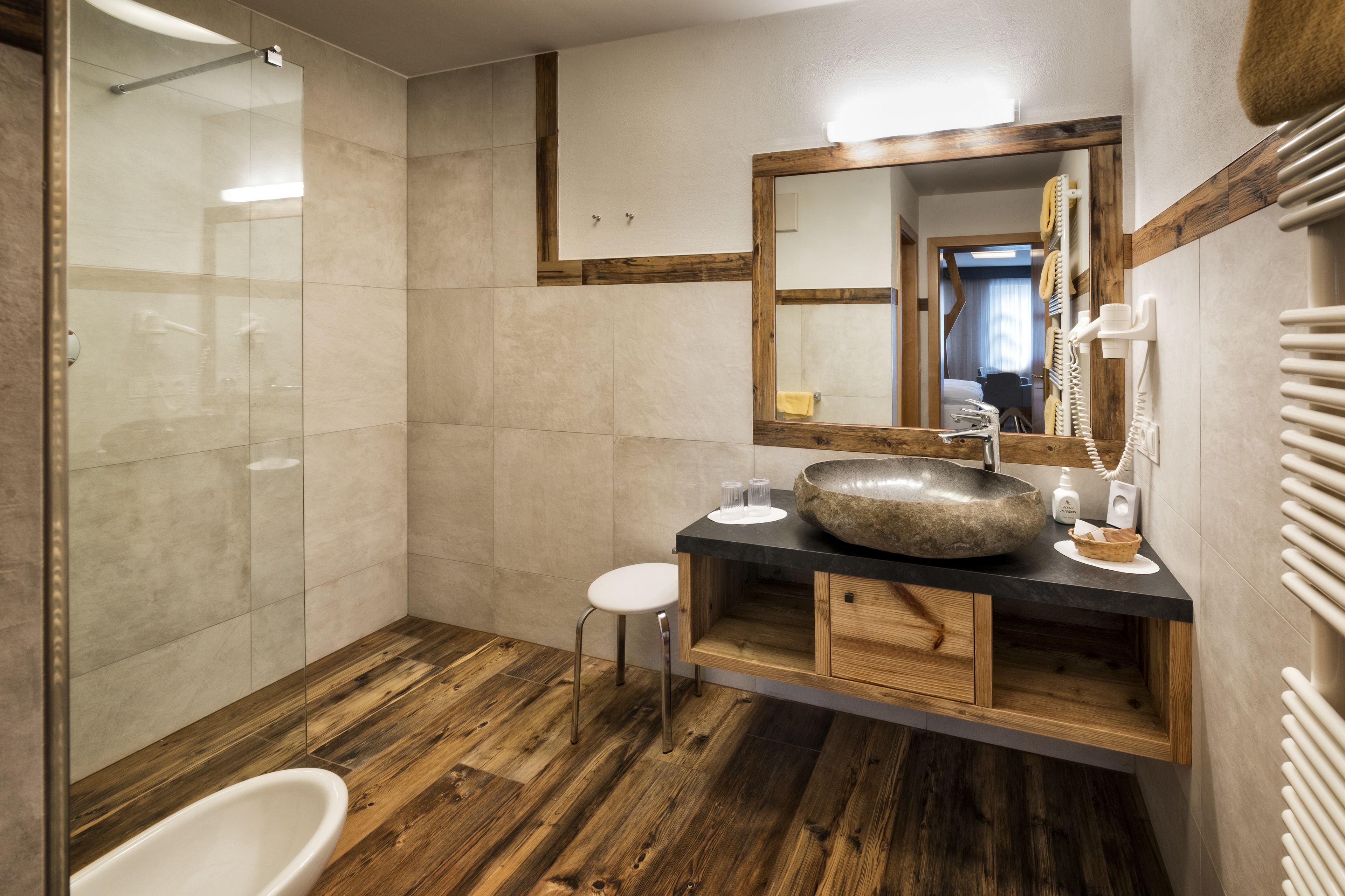 Een moderne badkamer met een grote spiegel, een houten wastafelmeubel en een douchecabine van glas.