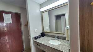 Un bagno con un piano in granito, un lavandino bianco e uno specchio.