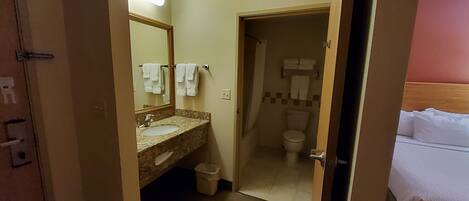 Un baño de hotel con lavamanos, espejo y retrete.