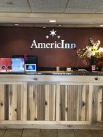 A reception desk with a sign reading "AmericInn" and a floral arrangement.