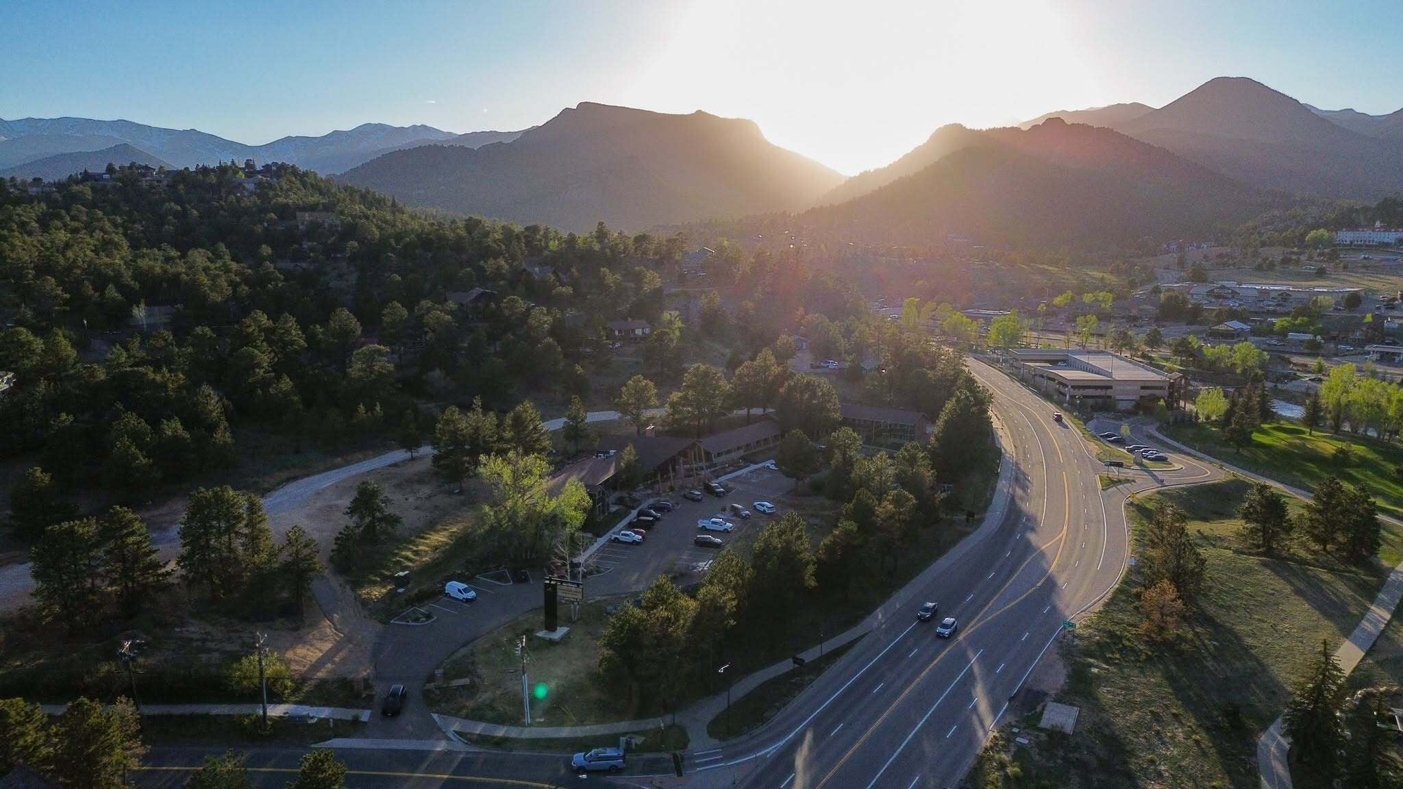 A highway with multiple lanes and vehicles, surrounded by trees and a mountainous landscape.