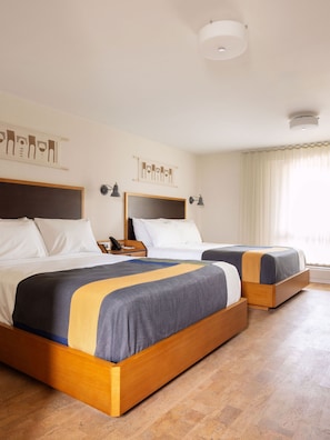 A hotel room with two wooden beds, a nightstand with a lamp, and a ceiling light fixture.