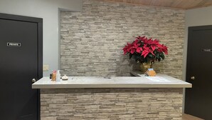 A reception desk with a stone wall backdrop, a vase with red flowers, and two 'PRIVATE' doors. - Valley Hi Motel - Near Winter Park Visitor Center (Winter Park)