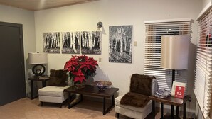 A living room with two armchairs, a coffee table, a potted plant, and wall art. - Valley Hi Motel - Near Winter Park Visitor Center (Winter Park)