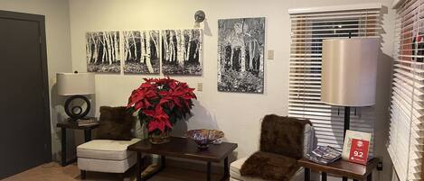 A living room with two armchairs, a coffee table, a potted plant, and wall art.