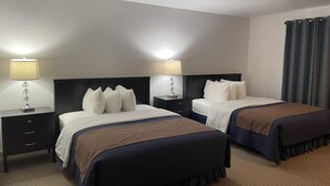 A hotel room with two beds, each with a headboard, bedside tables with lamps, and a large window with curtains. - Valley Hi Motel - Near Winter Park Visitor Center (Winter Park)