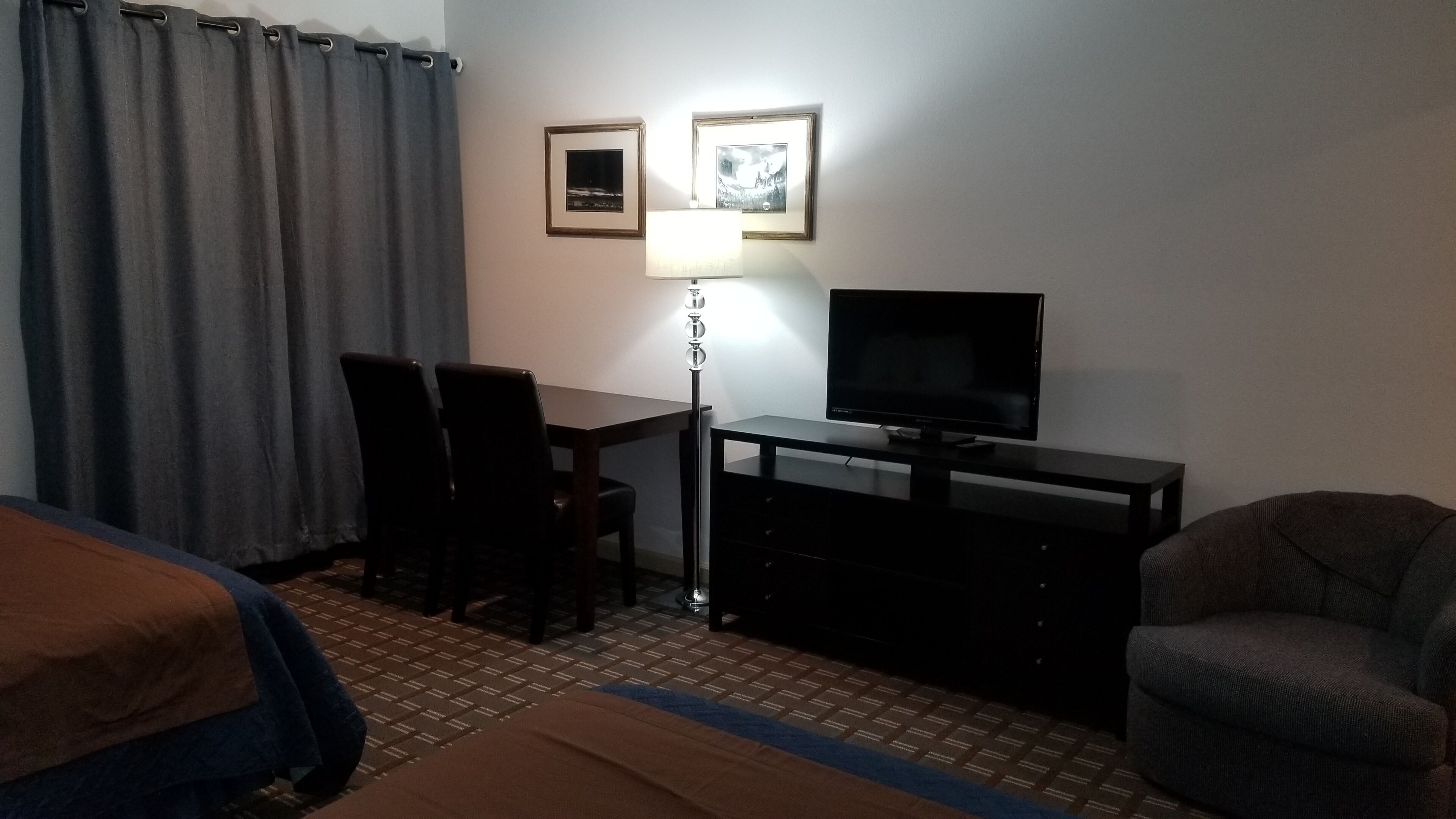 Una camera d'albergo con un letto, una scrivania con una sedia, una televisione e una lampada.