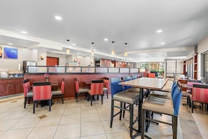 A restaurant with booths and tables, a counter, and a view of the outdoors. - Comfort Suites Vacaville-Napa Valley Area (Vacaville)