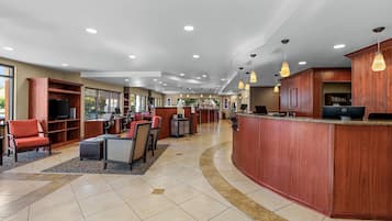 A hotel lobby with a reception desk, seating area, and a television.