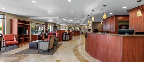 A hotel lobby with a reception desk, seating area, and a television.