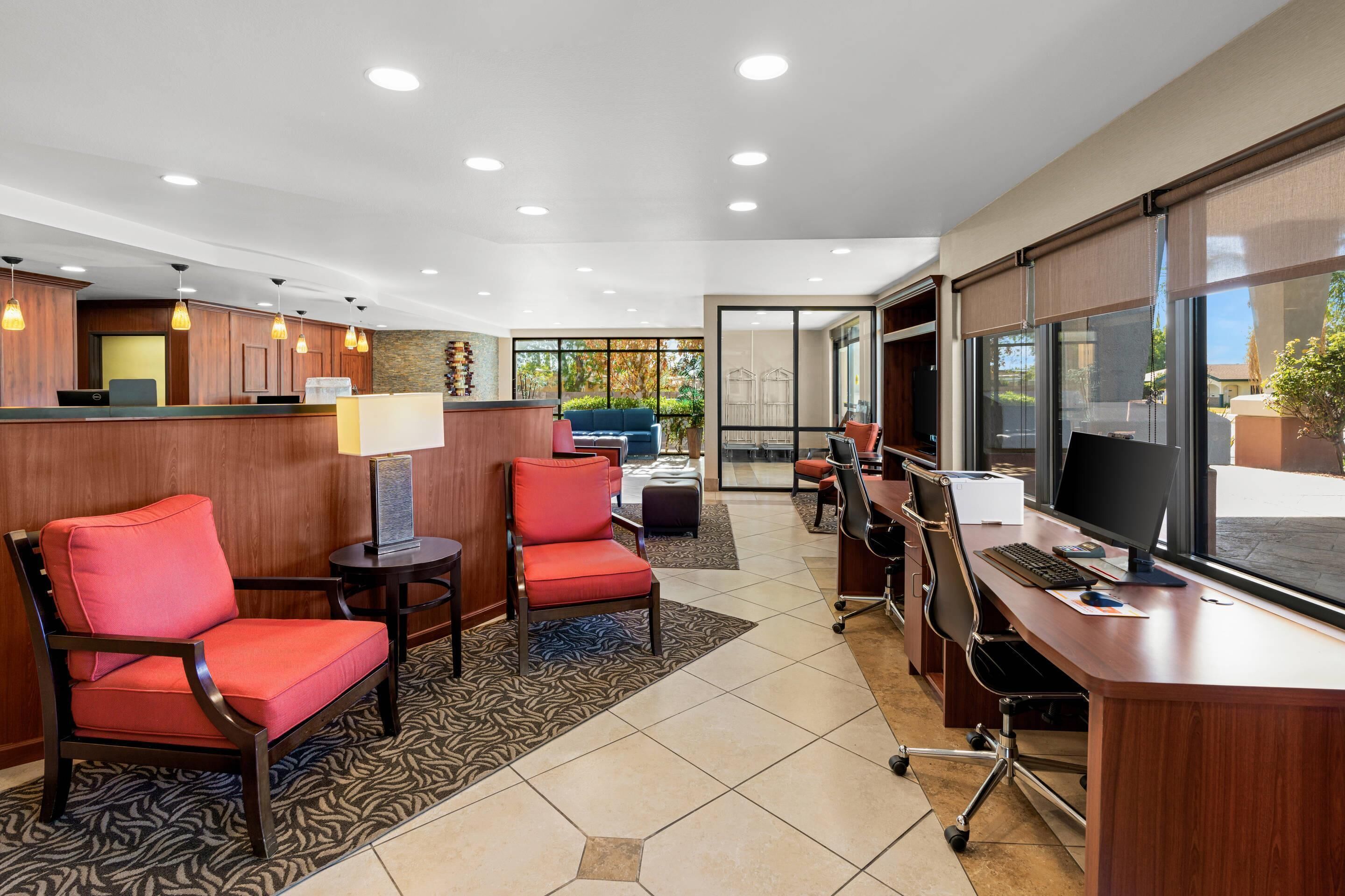 A hotel reception area with a desk, chairs, and a large window.