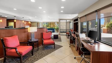A hotel reception area with a desk, chairs, and a large window.
