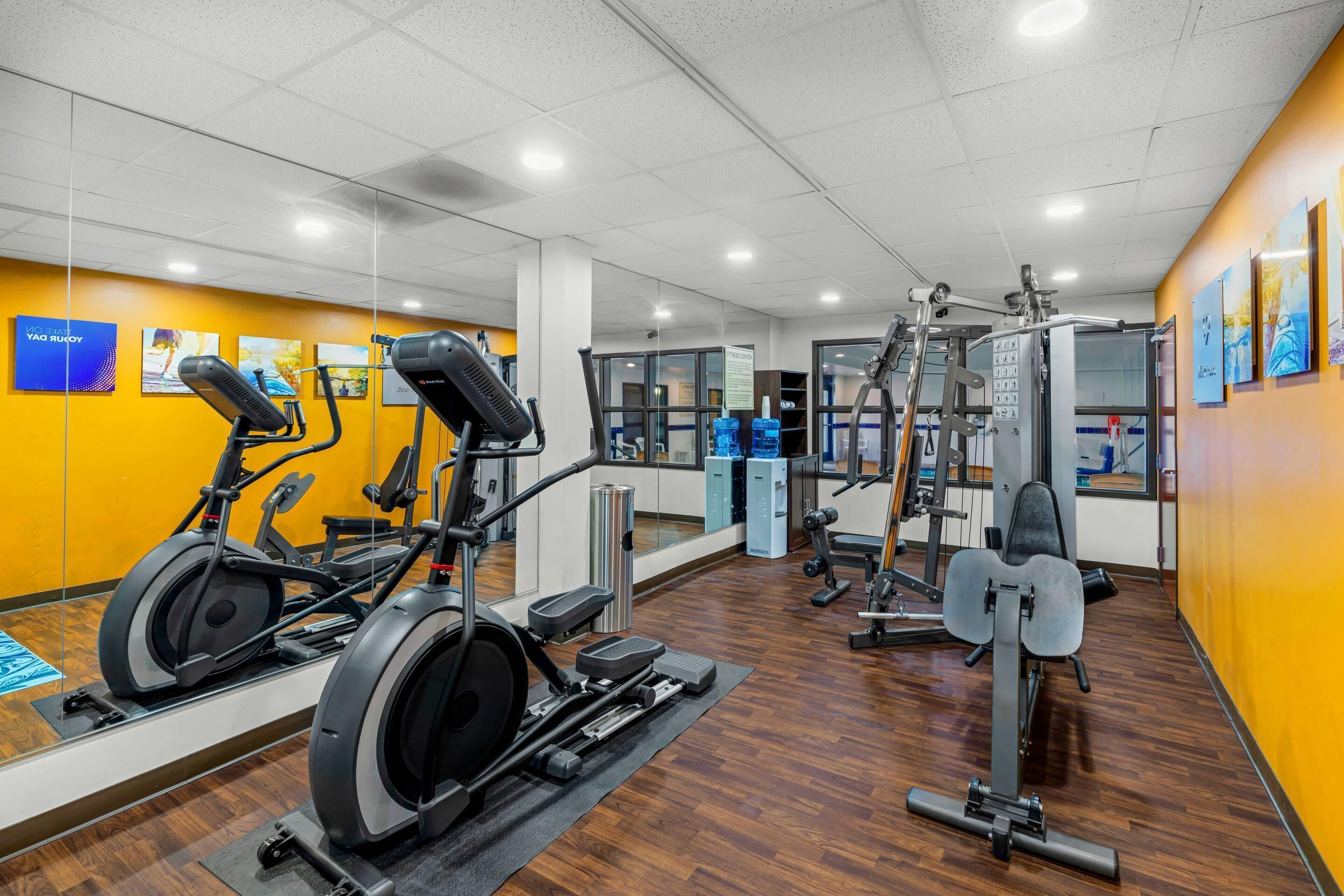 A gym with exercise equipment, a mirror, and a sign indicating a fitness center.