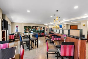 Un restaurante con varias mesas y cabinas, una barra con menú a la vista y un televisor en la pared.
