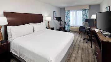 Habitación de hotel con una cama grande, un escritorio, un televisor de pantalla plana, una silla, una lámpara y una bicicleta.