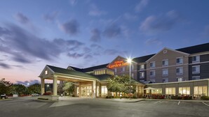 Un hôtel dont l’entrée est bien visible, avec une enseigne indiquant « Hilton Garden Inn », et un parking.
