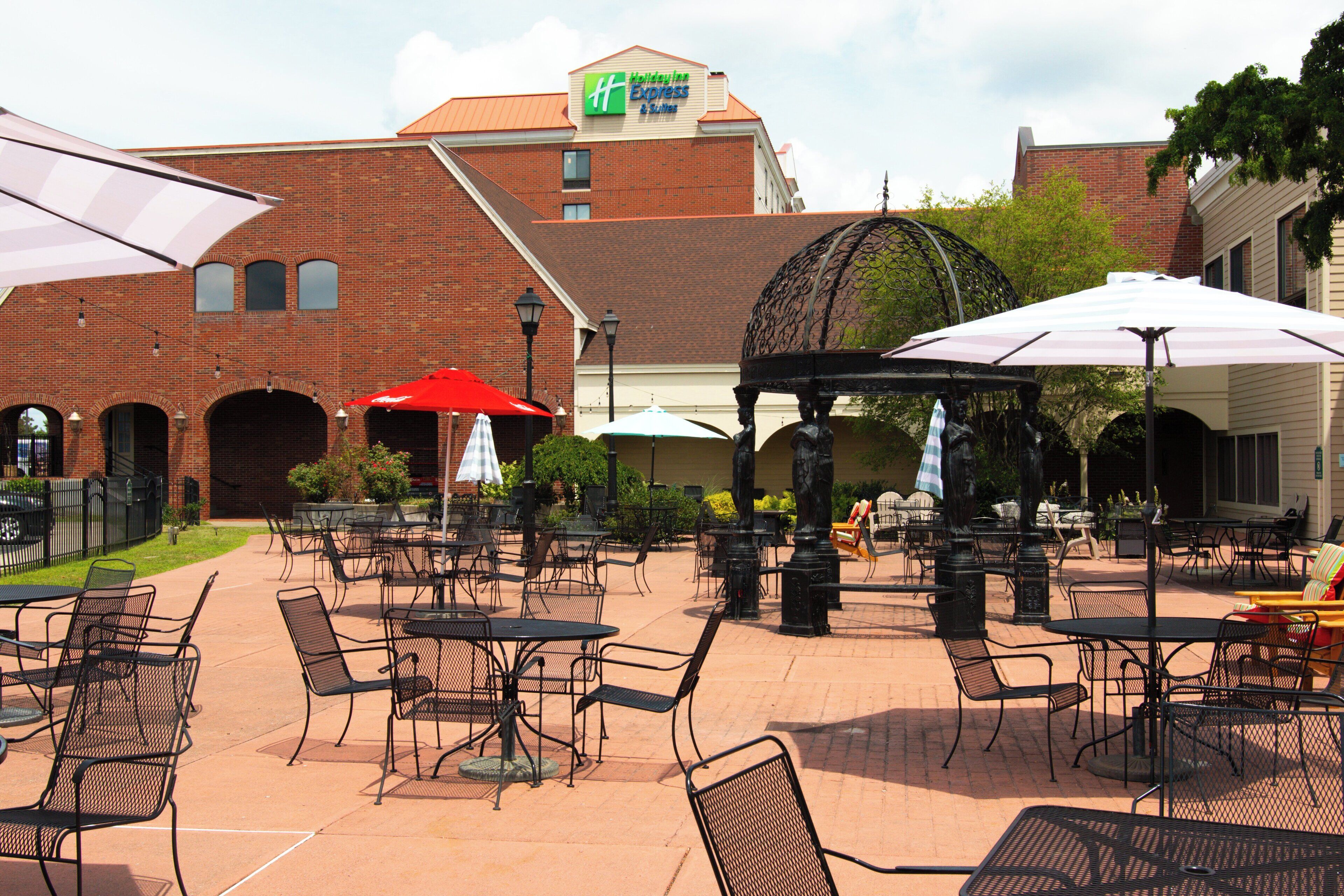 An outdoor patio area with tables and chairs, a gazebo, and umbrellas.