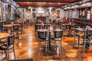 Un restaurante con varias mesas y sillas, piso pulido y cuadros enmarcados en las paredes.