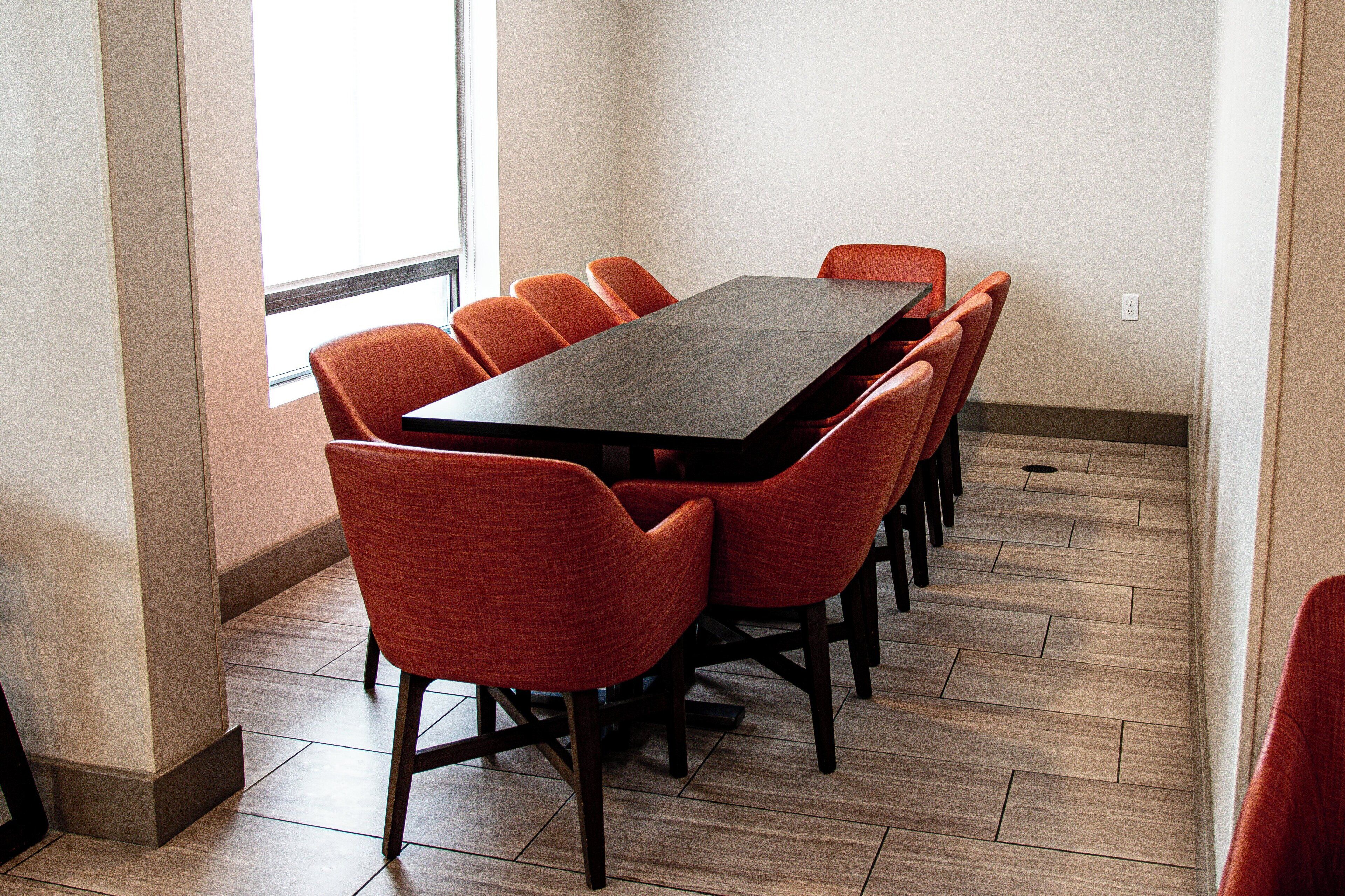 A conference room with a dark wooden table and orange chairs.