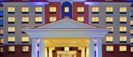 A Holiday Inn Express & Suites hotel with a symmetrical facade, multiple windows, and a central entrance with a covered walkway.