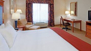 A hotel room with a bed, a desk, a chair, a television, and a window with curtains.