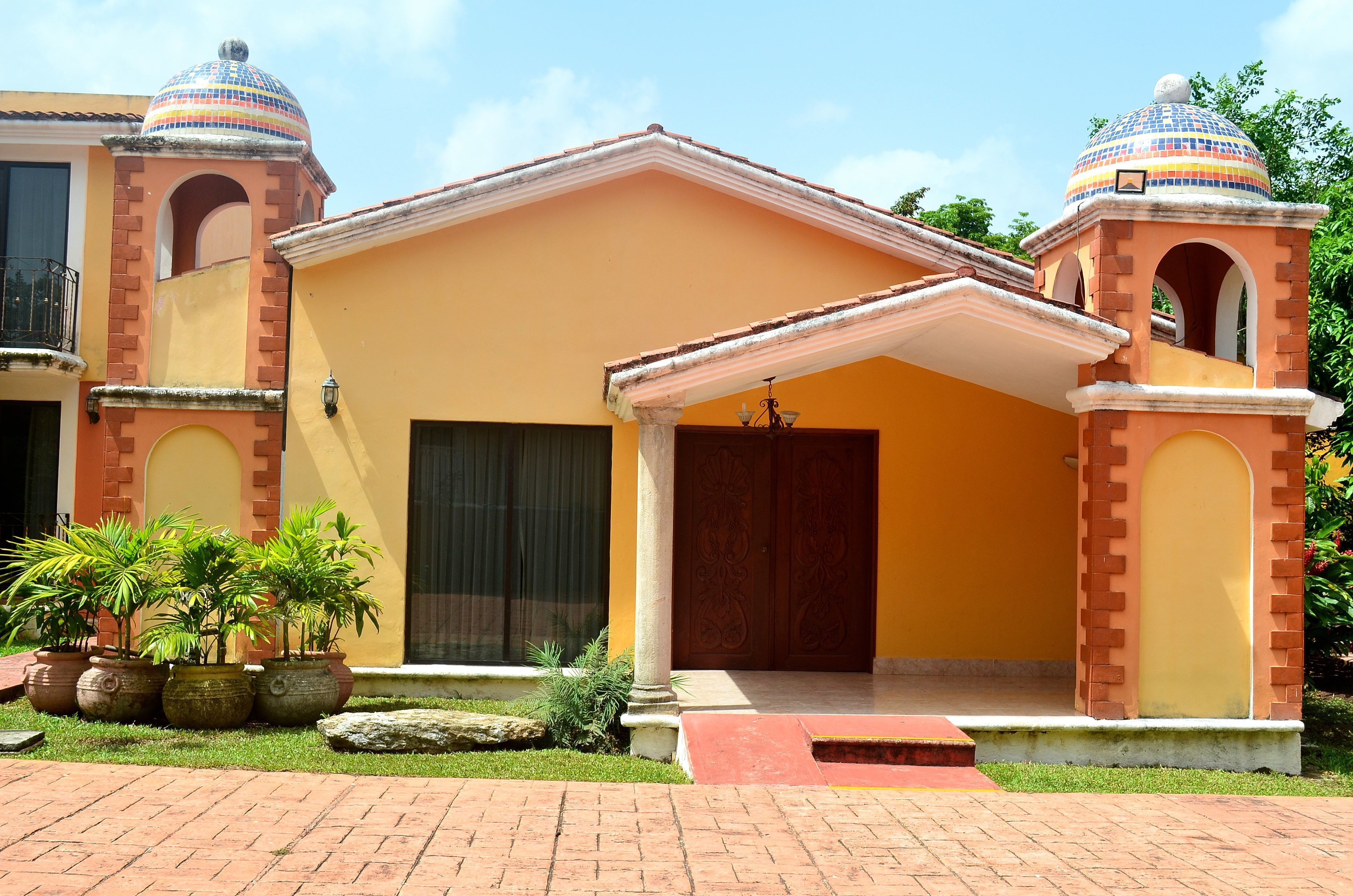 A building with a yellow facade, a central entrance with a door, and two domed towers.