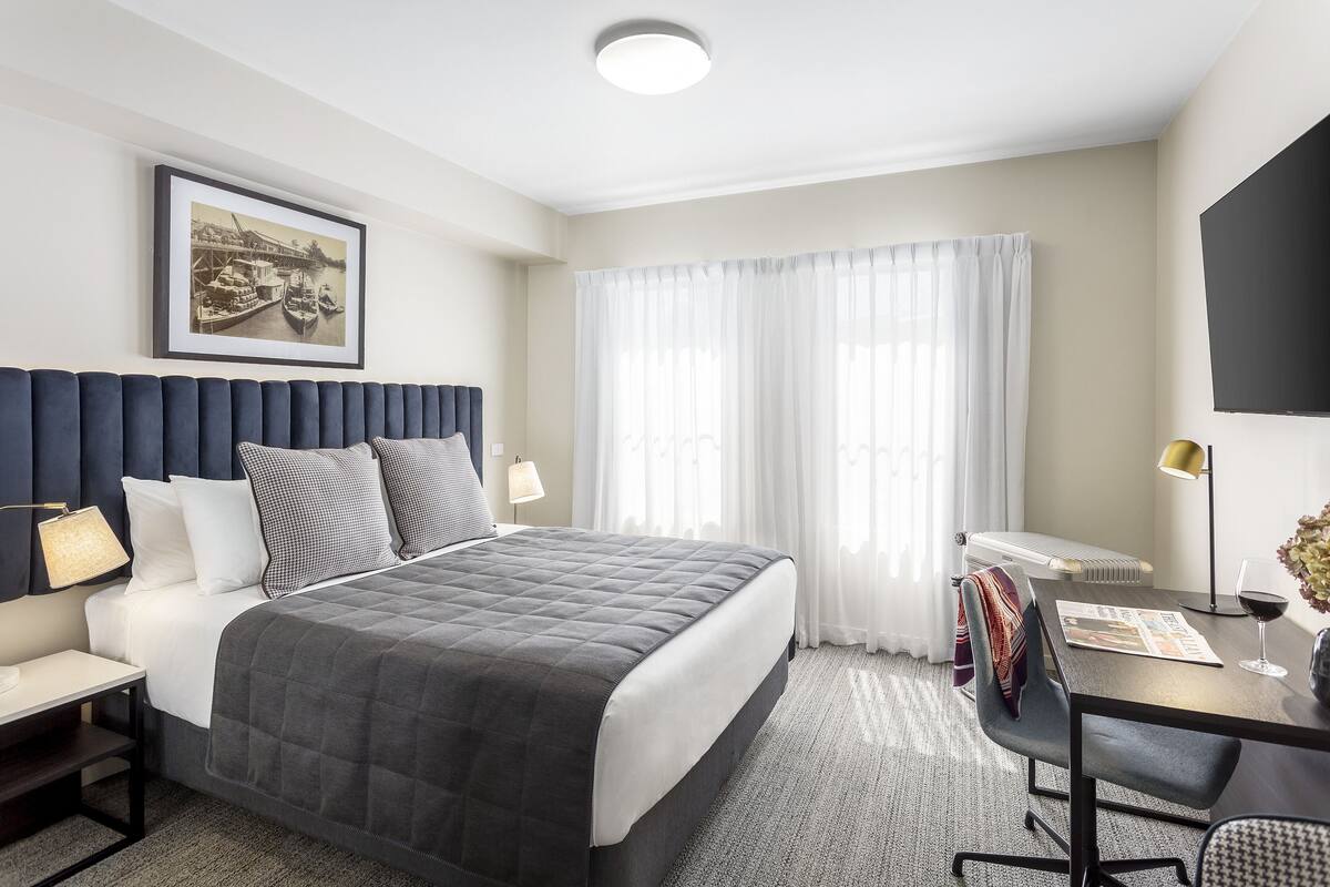Una habitación de hotel moderna con una cama grande, un escritorio y una televisión.