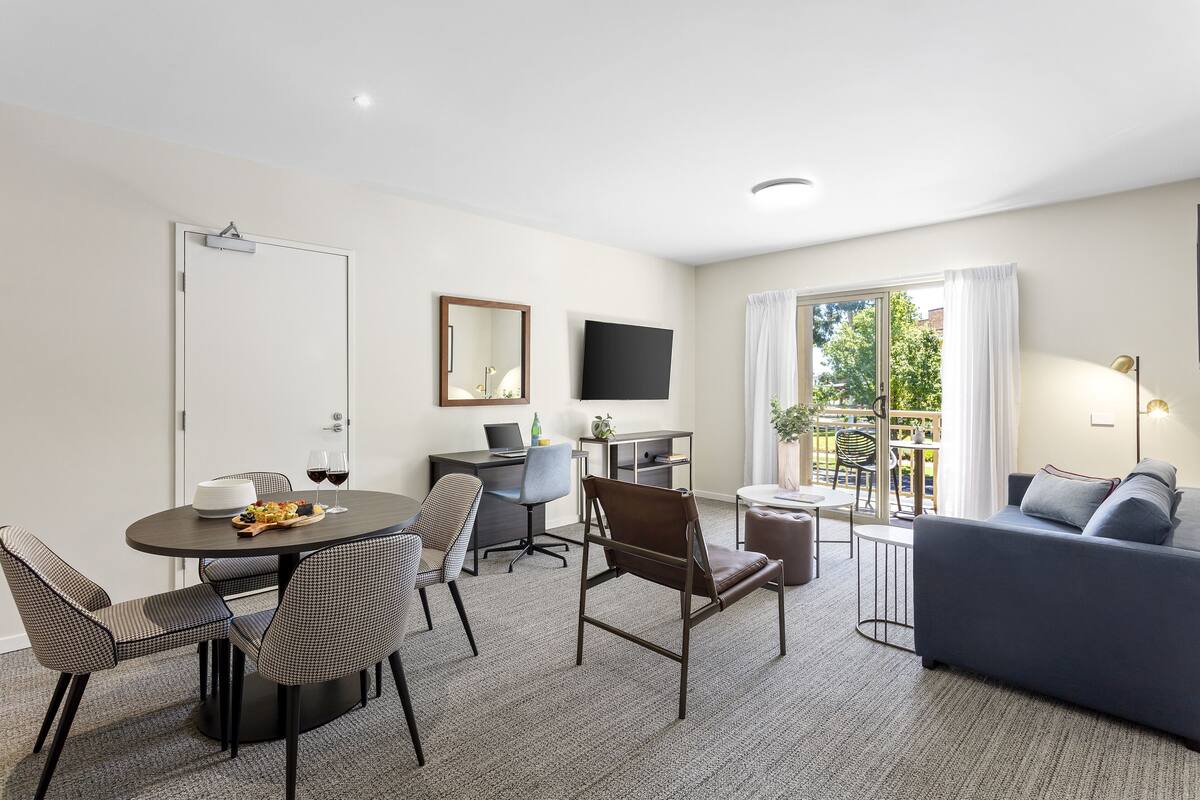 Una sala de estar moderna con comedor, sofá, televisor y balcón con vistas.