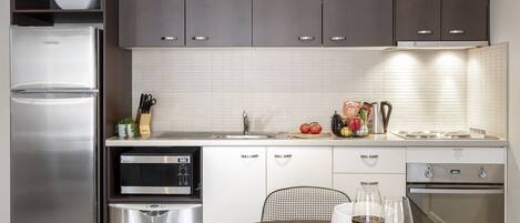Una cocina moderna con armarios oscuros, electrodomésticos de acero inoxidable y un comedor con una mesa dispuesta para una comida.
