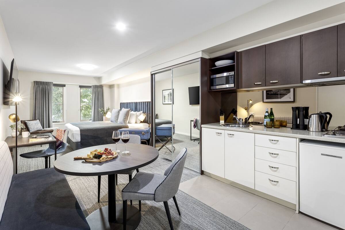 Una habitación de hotel moderna con comedor, kitchenette y una cama con vistas.