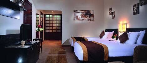 Une chambre d’hôtel comprenant un lit, un bureau, une télévision et une porte donnant sur une autre pièce.