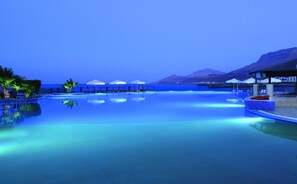 Una piscina infinita tranquila con vistas despejadas al océano y montañas al fondo.
