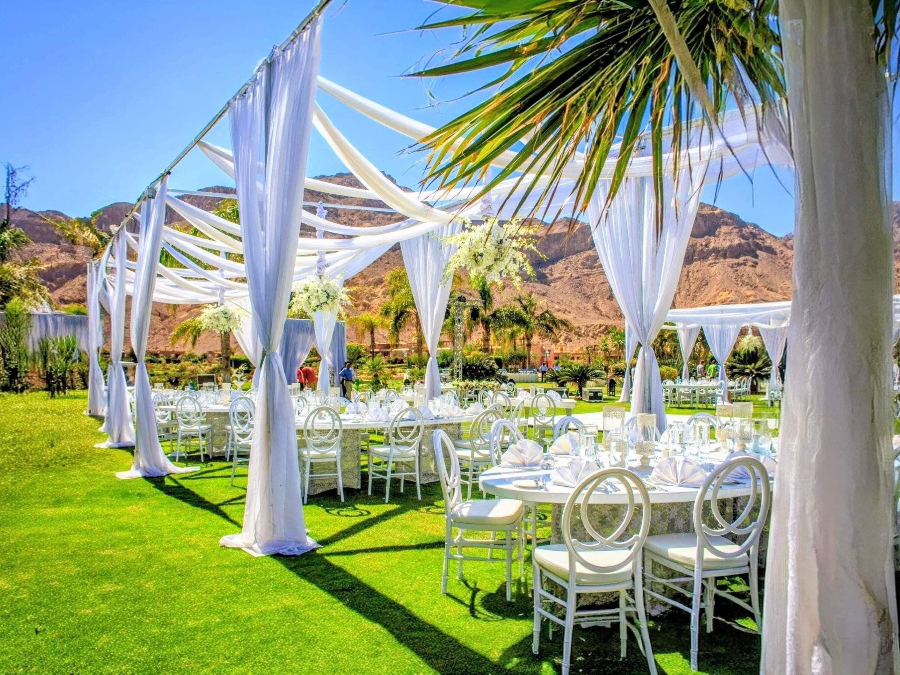 Un lugar para bodas al aire libre con toldos blancos, mesas redondas y sillas.
