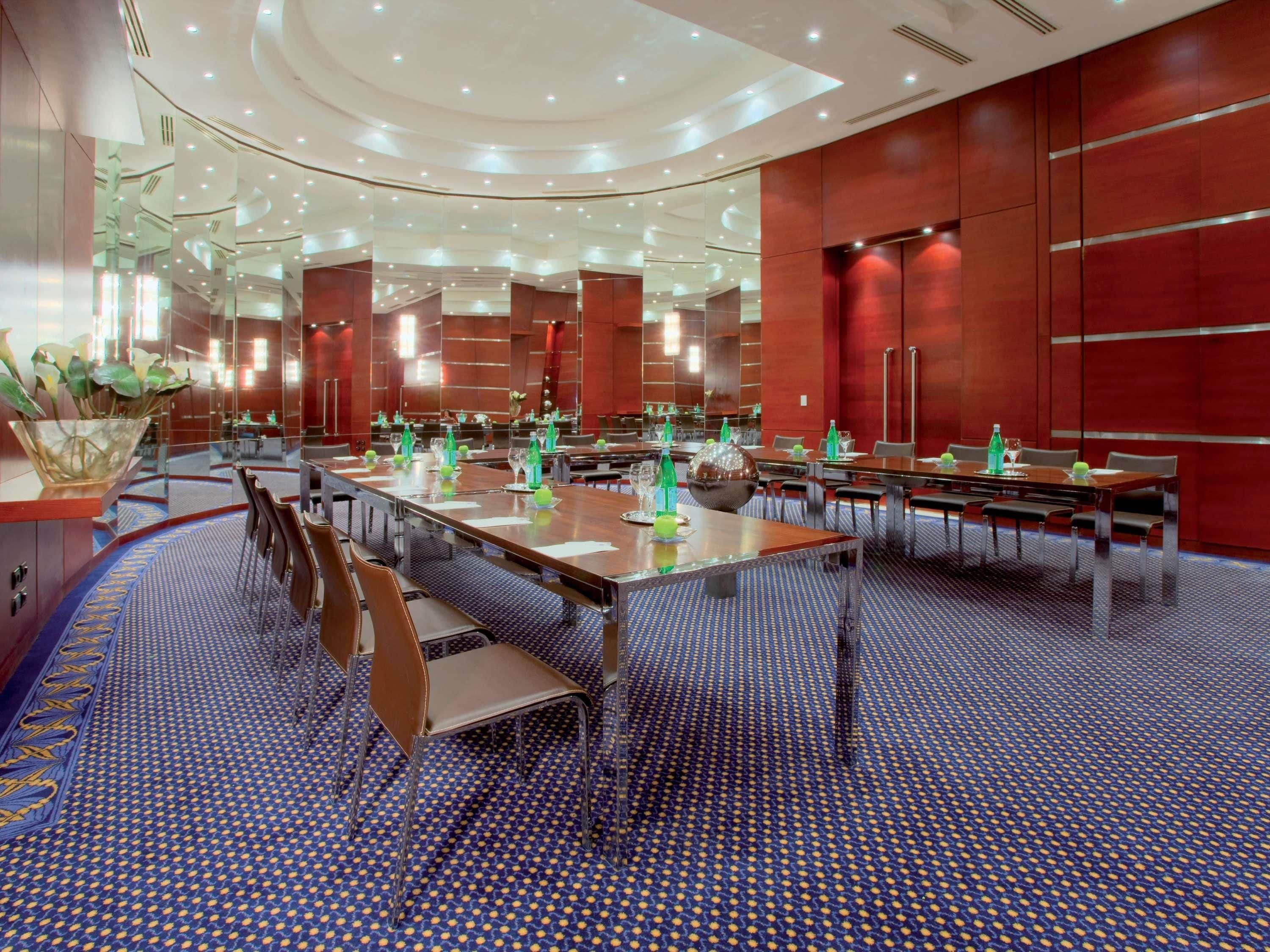 A modern conference room with a long table, chairs, and a patterned carpet.