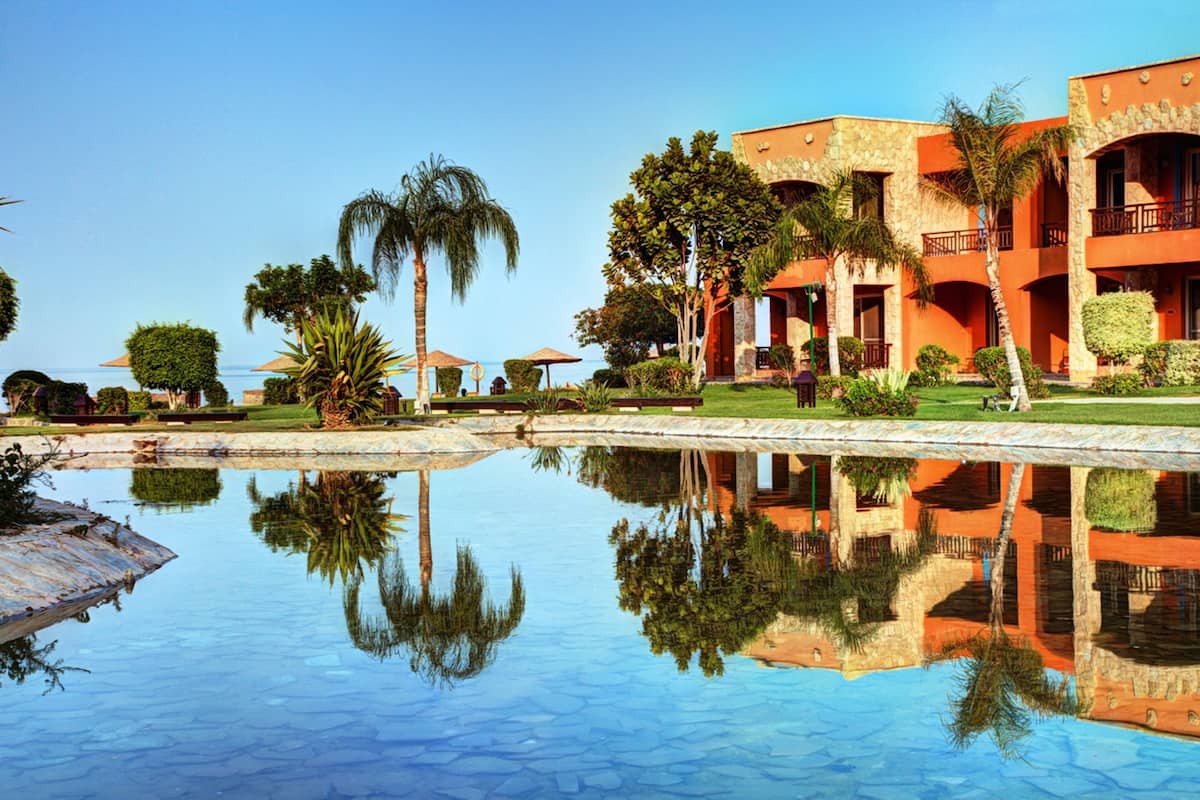 Een resort met een zwembad, palmbomen en een gebouw met balkons.