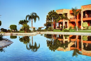 Un resort con piscina, palmeras y un edificio con balcones.