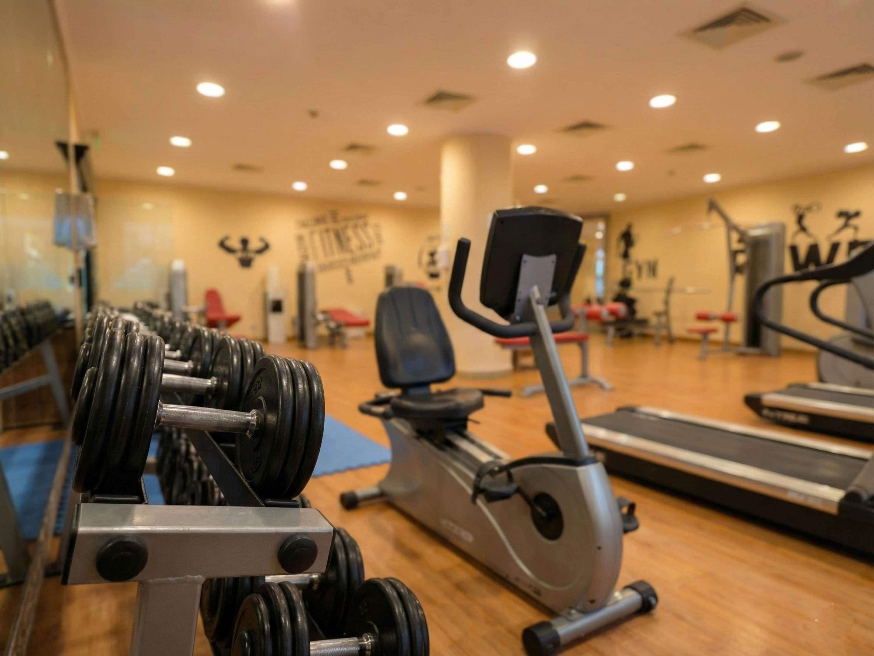 A gym with exercise equipment including dumbbells, an elliptical trainer, and a treadmill.