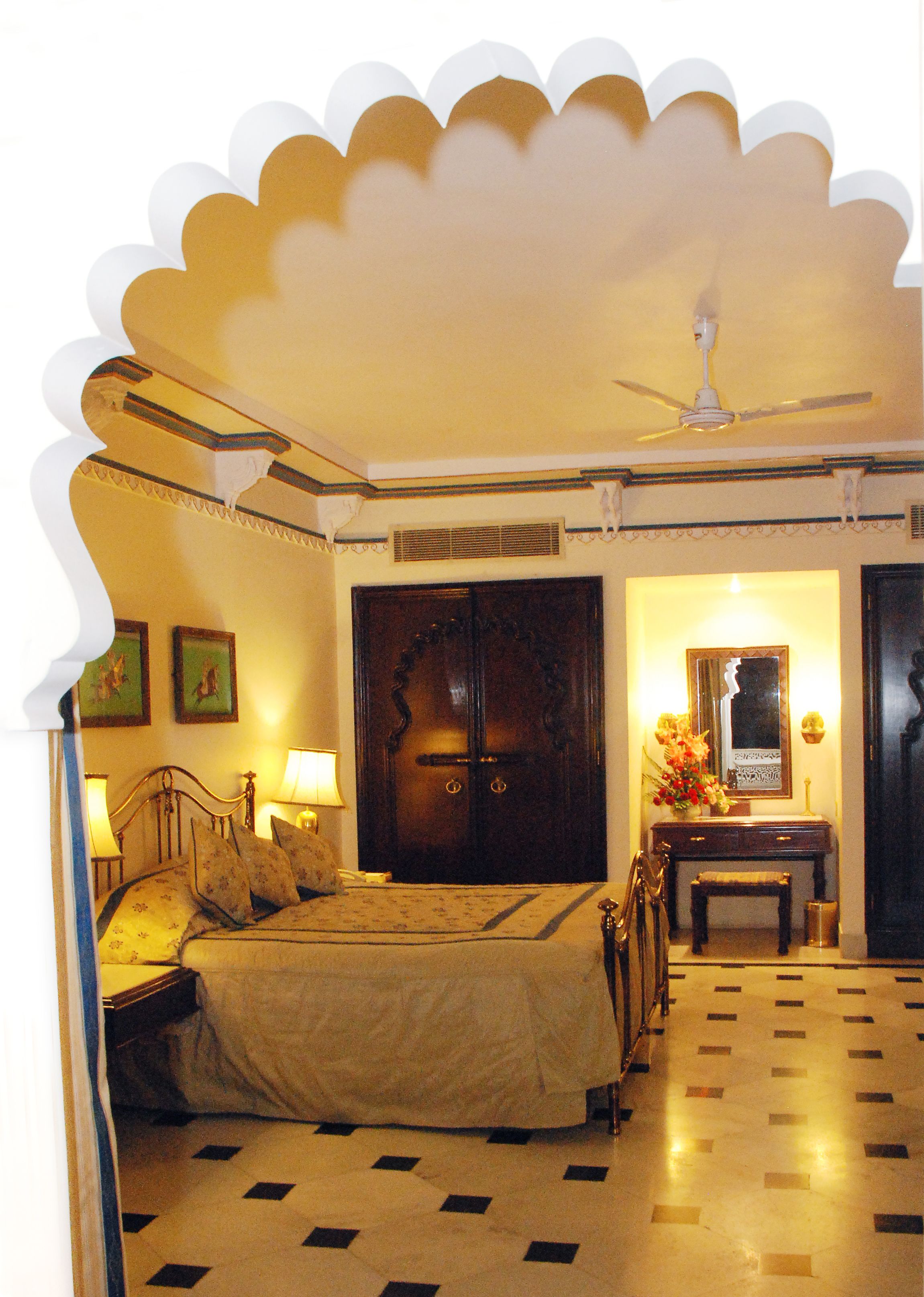 Une chambre traditionnelle avec un lit, des lampes de chevet, une armoire en bois, une petite table avec un vase et un miroir.