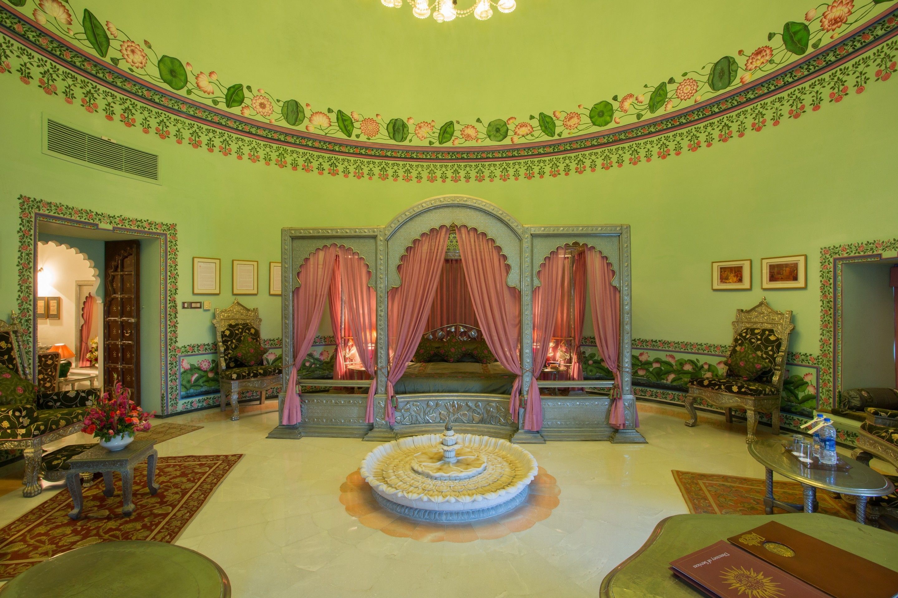 A room with a central fountain, ornate furniture, and floral wall decorations.