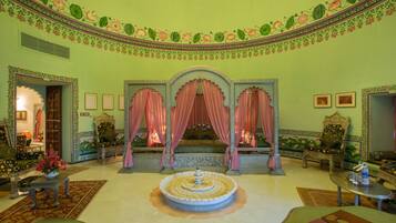A room with a central fountain, ornate furniture, and floral wall decorations.