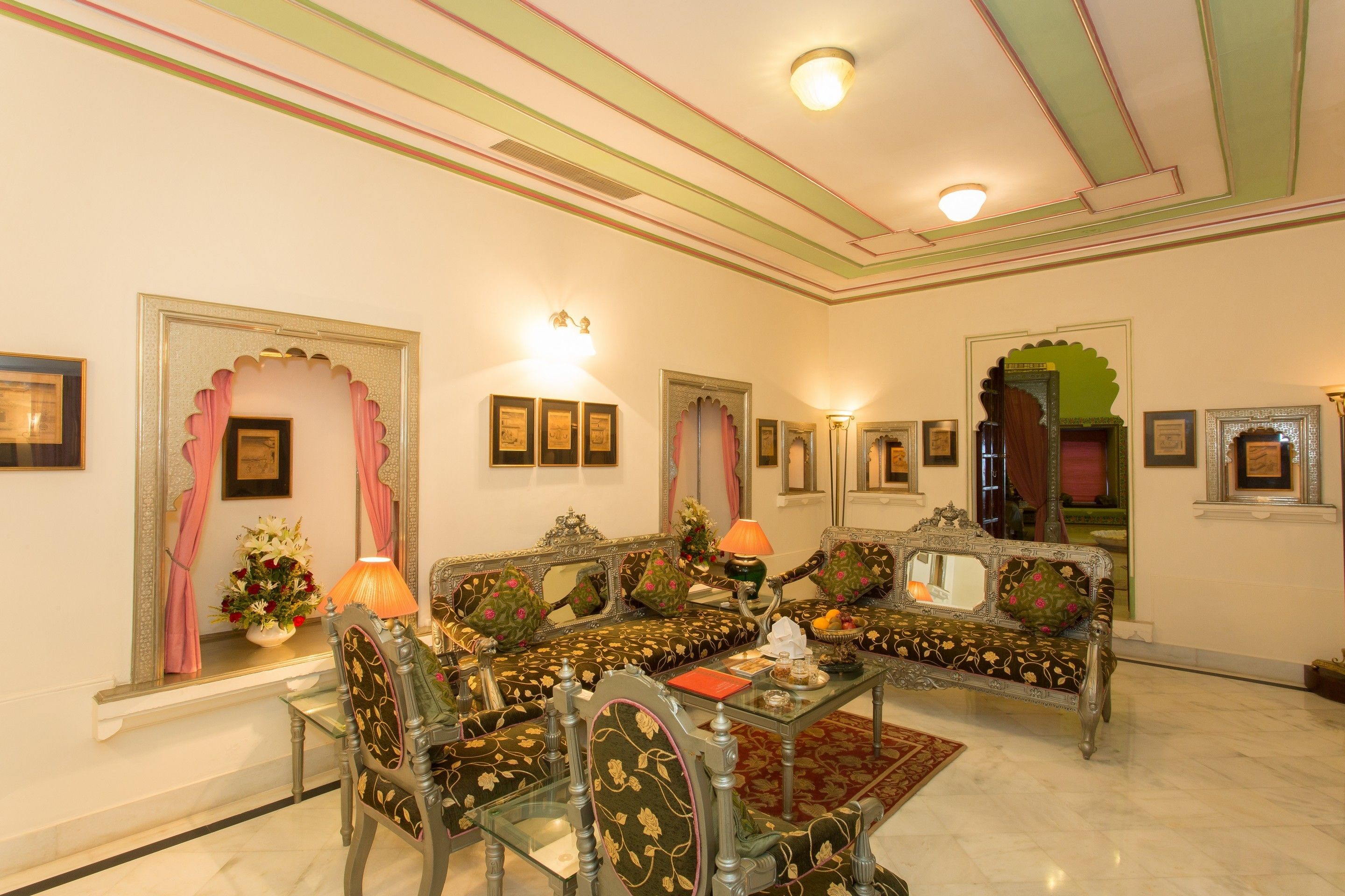 A traditional room with ornate furniture, a glass table, and framed artwork on the walls.