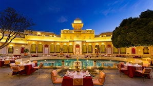 A courtyard with a pool, dining area, and a building with arches and a tower. - Shiv Niwas Palace by HRH Group of Hotels (Udaipur)