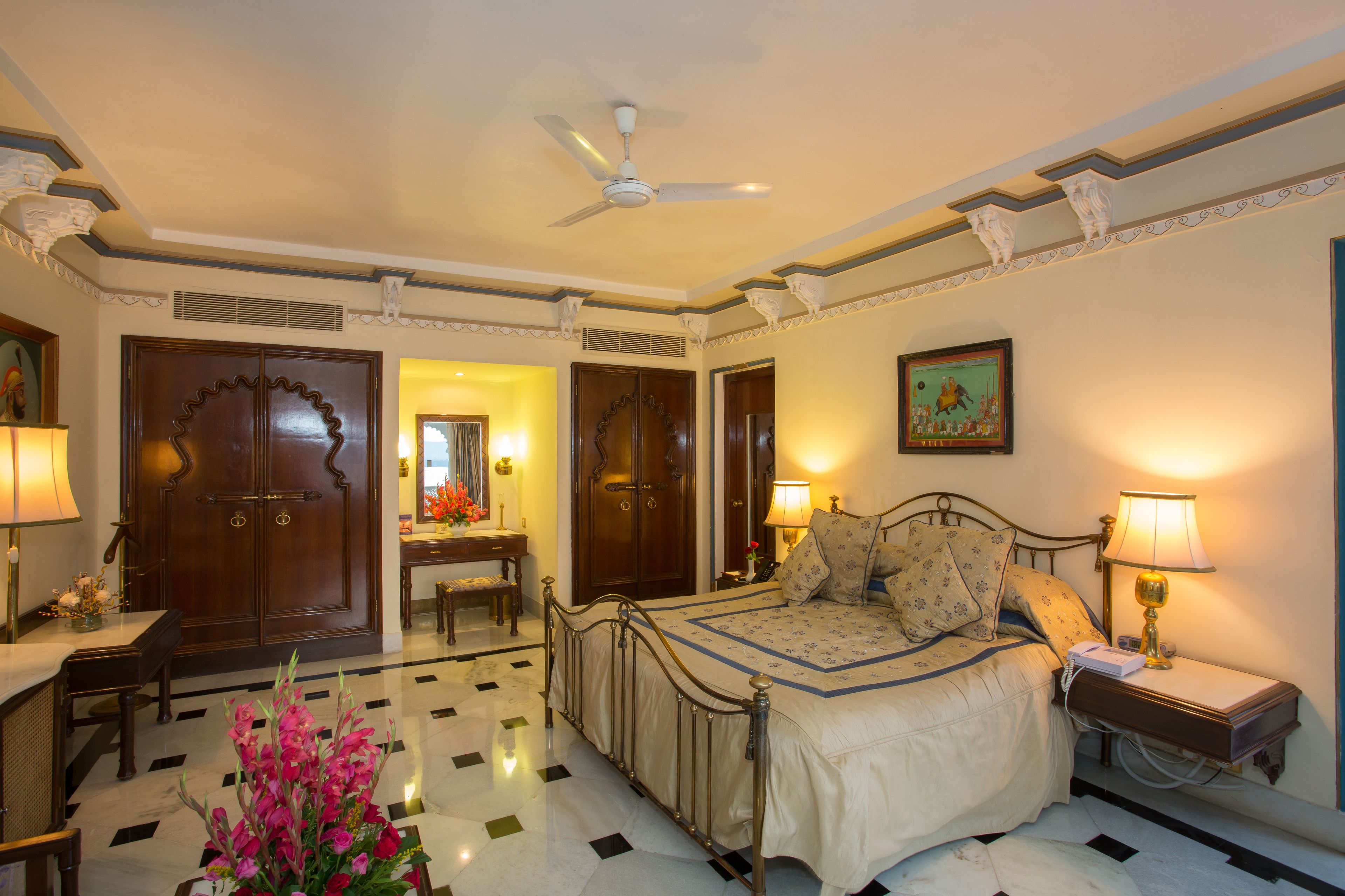 A hotel room with a bed, bedside table, lamp, and a ceiling fan.