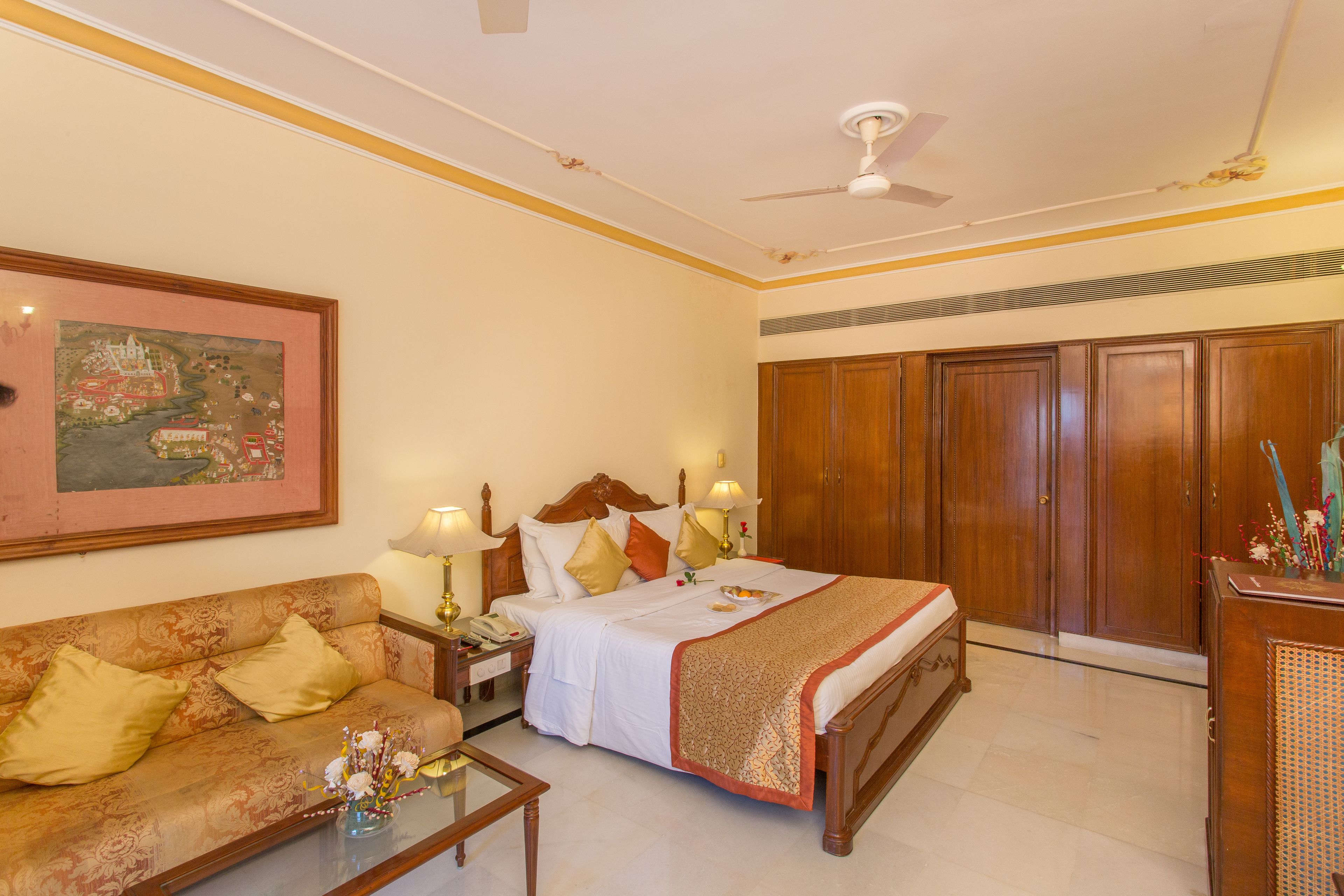 A hotel room with a bed, a sofa, a desk, and a wardrobe.