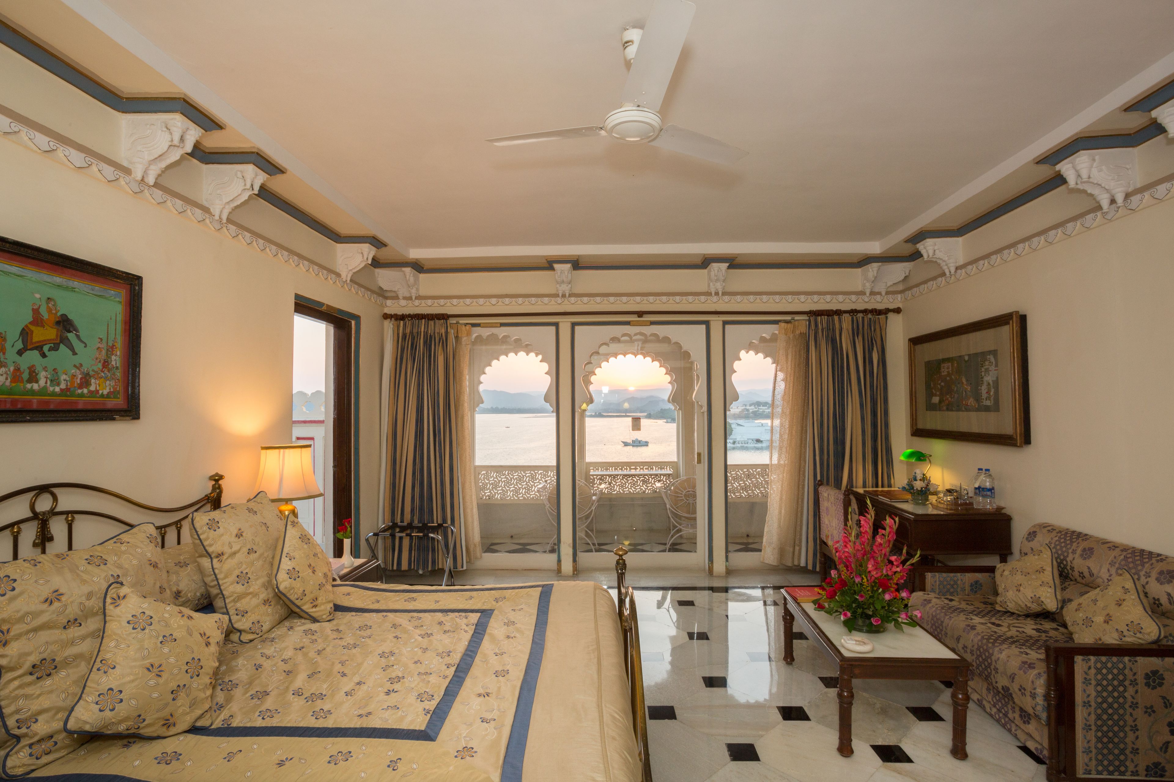A hotel room with a bed, a sofa, a table, and a balcony with a view.