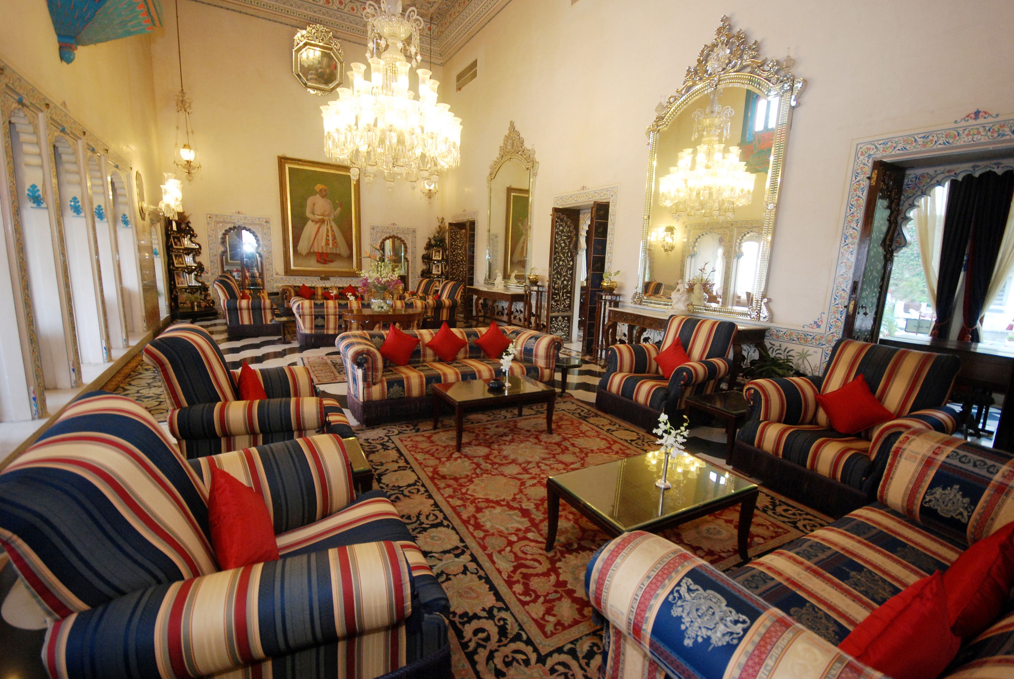 A traditional living room with striped sofas, a chandelier, and ornate mirrors.