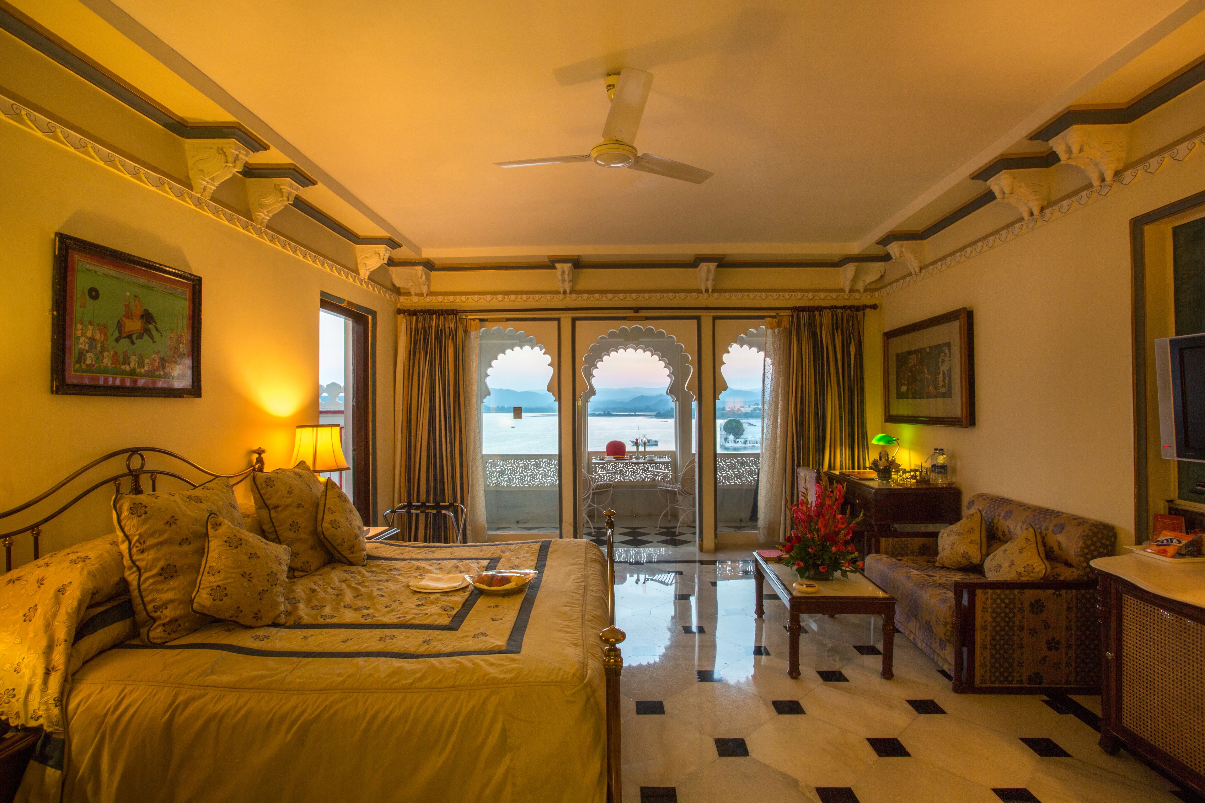 A hotel room with a bed, a sofa, a table, and a balcony with a view.