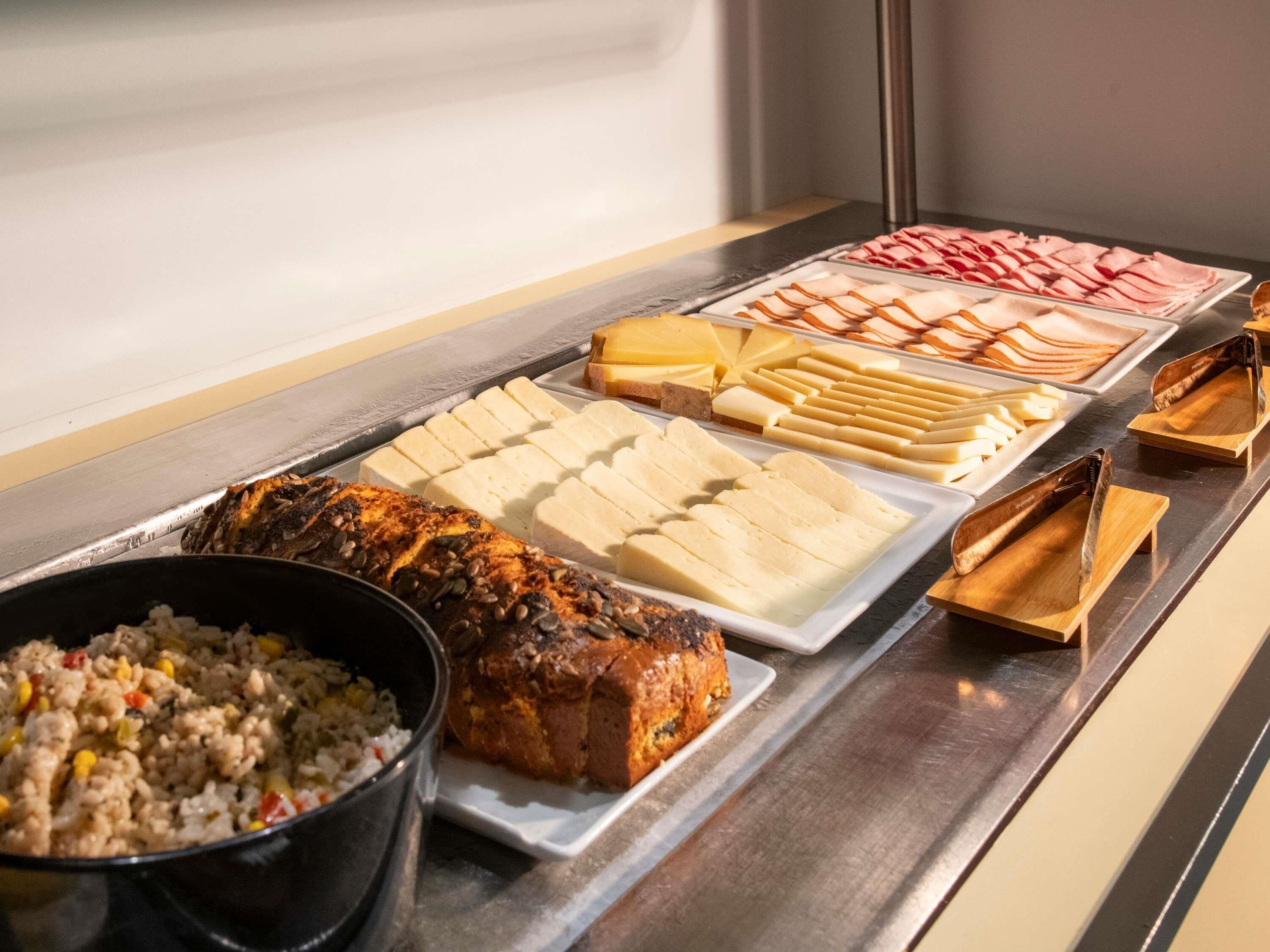 A buffet with various food items including meats, cheeses, and a dish of fried rice.