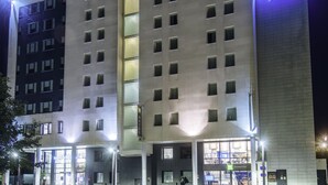 Een hotel met een moderne gevel, meerdere verdiepingen en een opvallend 'Novotel Suites'-bord.