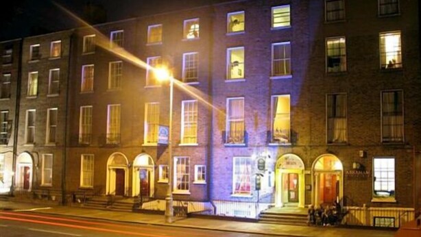 A multi-story building with illuminated windows and a street in front. - Glen Guesthouse (Dublin)